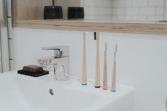 Bamboo toothbrushes with BPA-free bristles in bathroom setting, sustainable oral care.