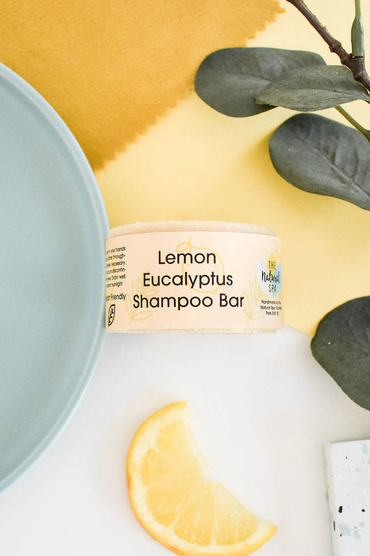 Plastic-free solid shampoo bar with eucalyptus and lemon oils, shown with lemon slices and spa-inspired decor.