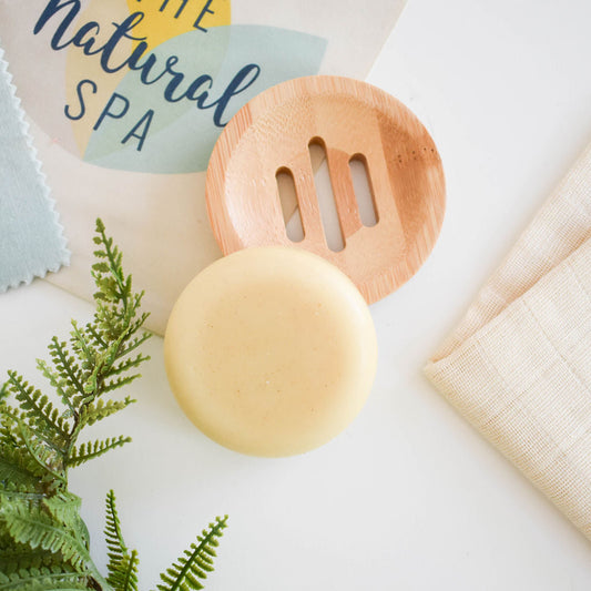 Spiced cedar solid conditioner bar styled on a plate with leaves.