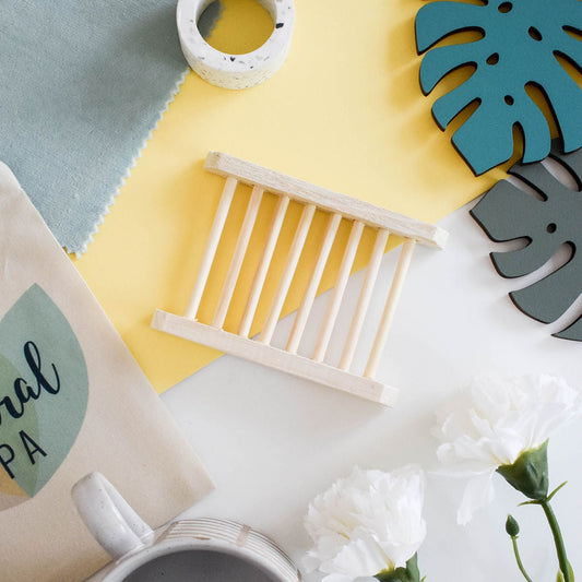 Natural bamboo ladder-style soap dish on a decorative spa background with flowers.