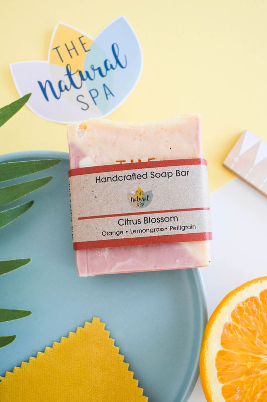 Citrus blossom soap bar with lemongrass, orange and palmarosa, handmade and plastic-free, styled with orange slices and green leaves.