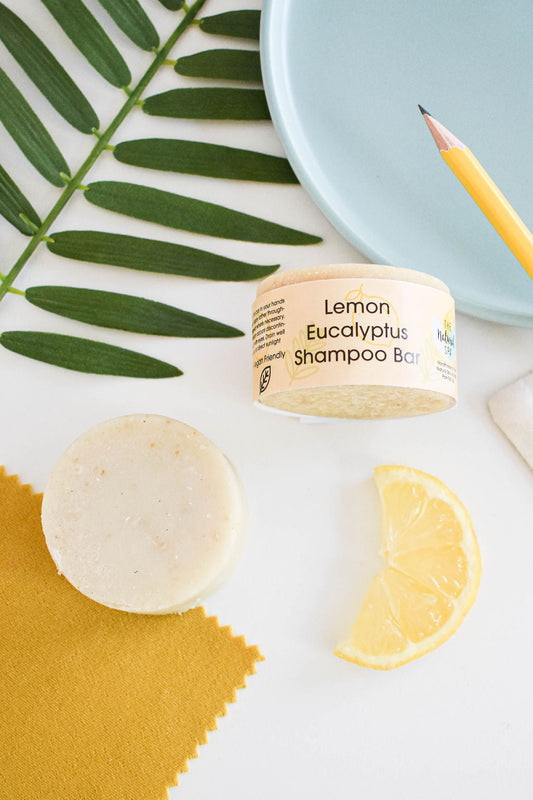 Eucalyptus and lemon solid shampoo bar styled with fresh lemon slices and green leaves on white background.