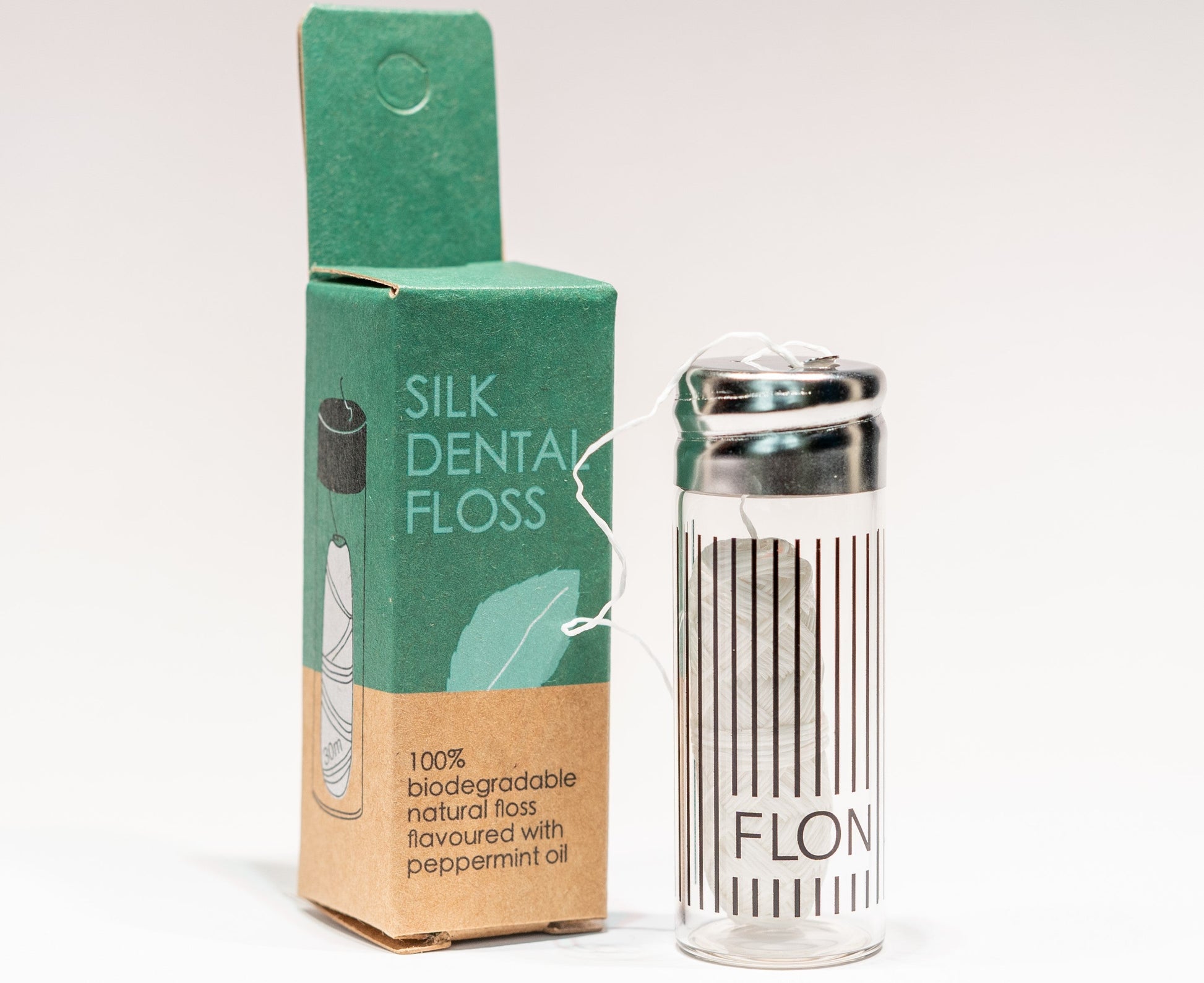Natural silk dental floss with refillable glass dispenser and eco-friendly packaging.