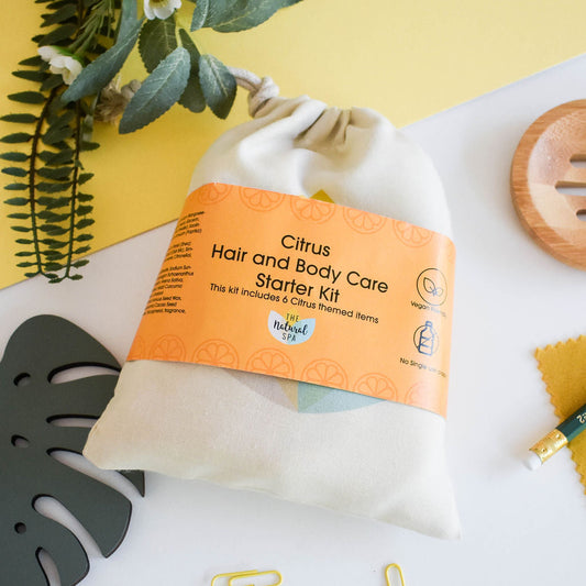 Plastic-free Citrus hair and body starter kit with white cotton bag and solid bars, styled with yellow background and green leaves.