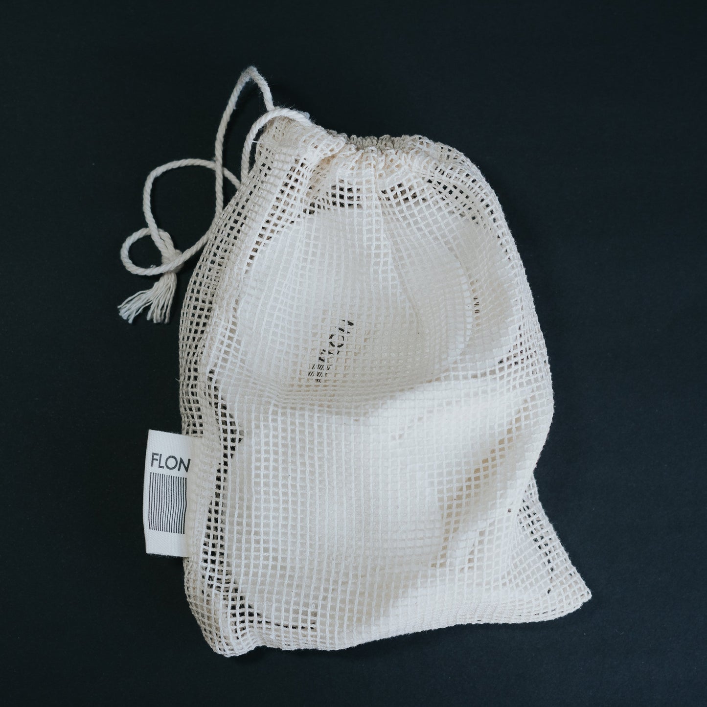 Reusable bamboo makeup remover pads with drawstring mesh wash bag displayed on a white surface.