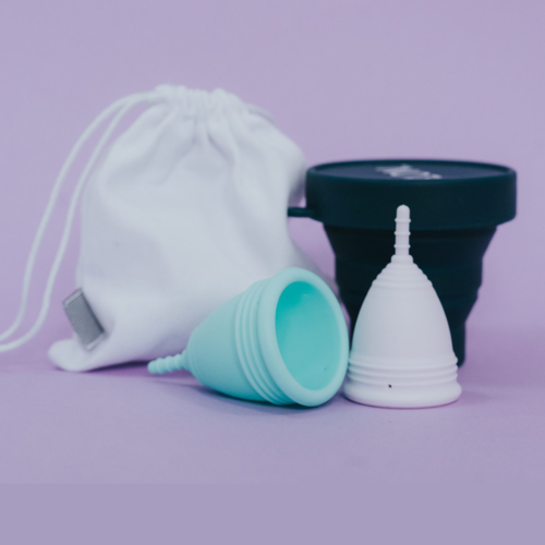 Cotton storage pouch, steriliser and two menstrual cups on lilac background.