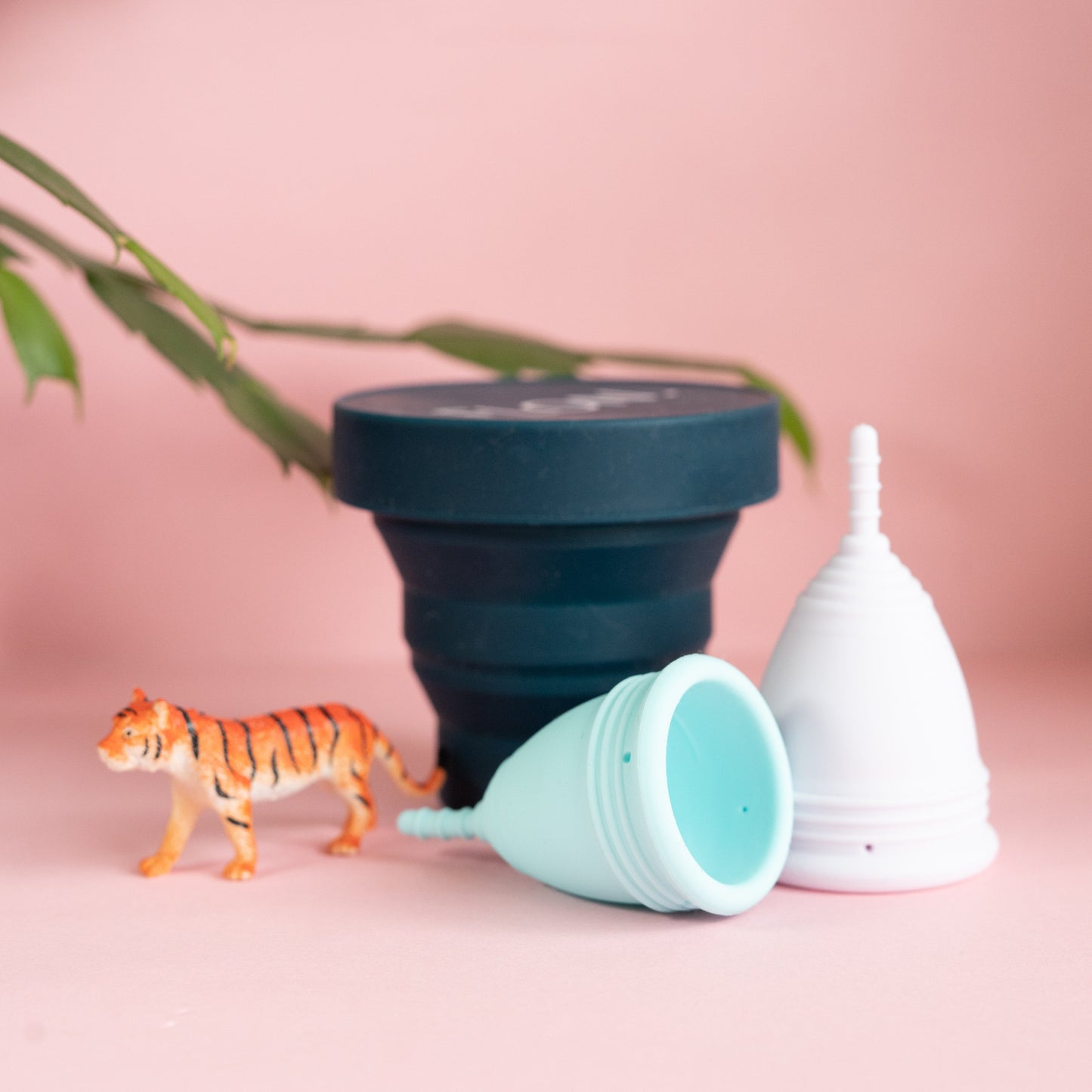 Foldable steriliser with menstrual cup and pouch on pink background.