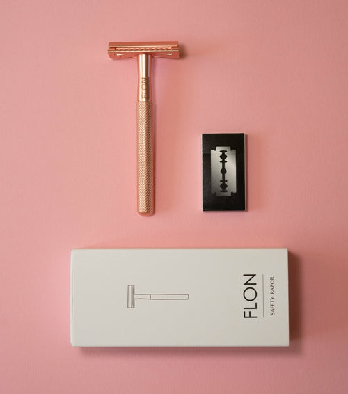 Rose gold reusable safety razor with stainless blade and FLON packaging on pink background.