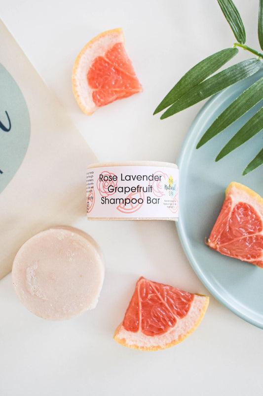Solid shampoo bar with rose, lavender and grapefruit, displayed on a plate with grapefruit slices and green leaves. Vegan, plastic-free, handmade shampoo bar.
