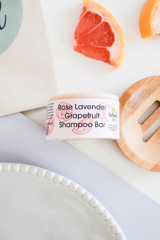 Handmade rose, lavender and grapefruit shampoo bar on a white plate with grapefruit wedges. Solid, zero-waste and eco-friendly hair care product.