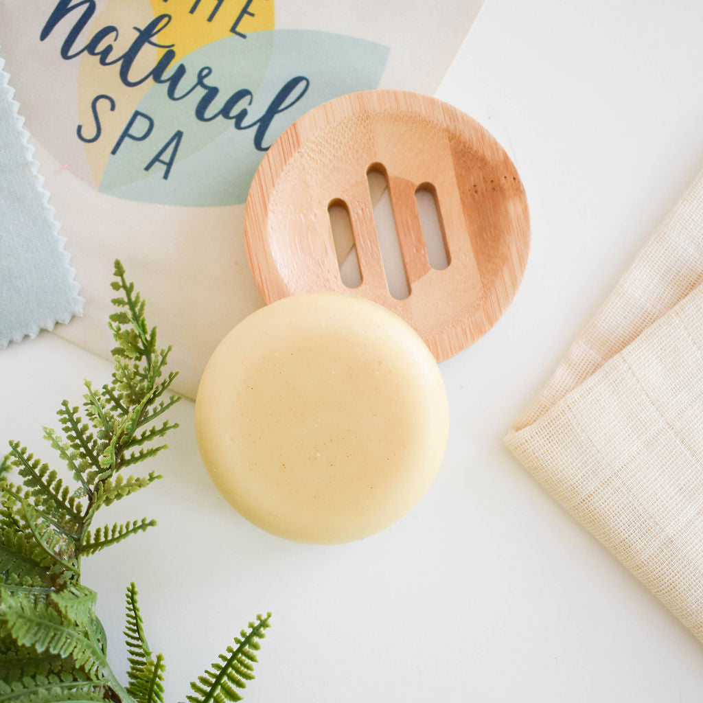 Spiced cedar solid conditioner bar styled on a plate with leaves.