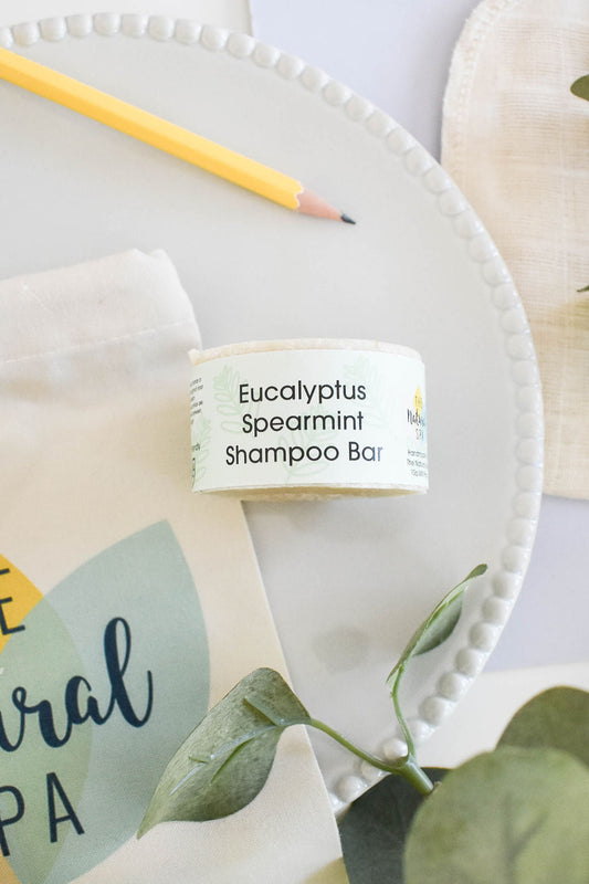 Handmade spearmint and eucalyptus shampoo bar styled with spa decor and green foliage.